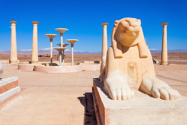 Imponerende egyptisk filmkulisse med majestætisk sfinks-statue og klassiske søjler i Atlas Film Studios i Ouarzazate, Marokko, omgivet af det karakteristiske ørkenlandskab