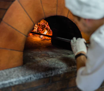 Ægte napolitansk margherita pizza bages i traditionel træfyret ovn med flammer i en restaurant i Napoli, Italien