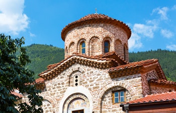Historisk ortodoks kloster med traditionel stenarkitektur og rødt tegltag i Bulgarien
