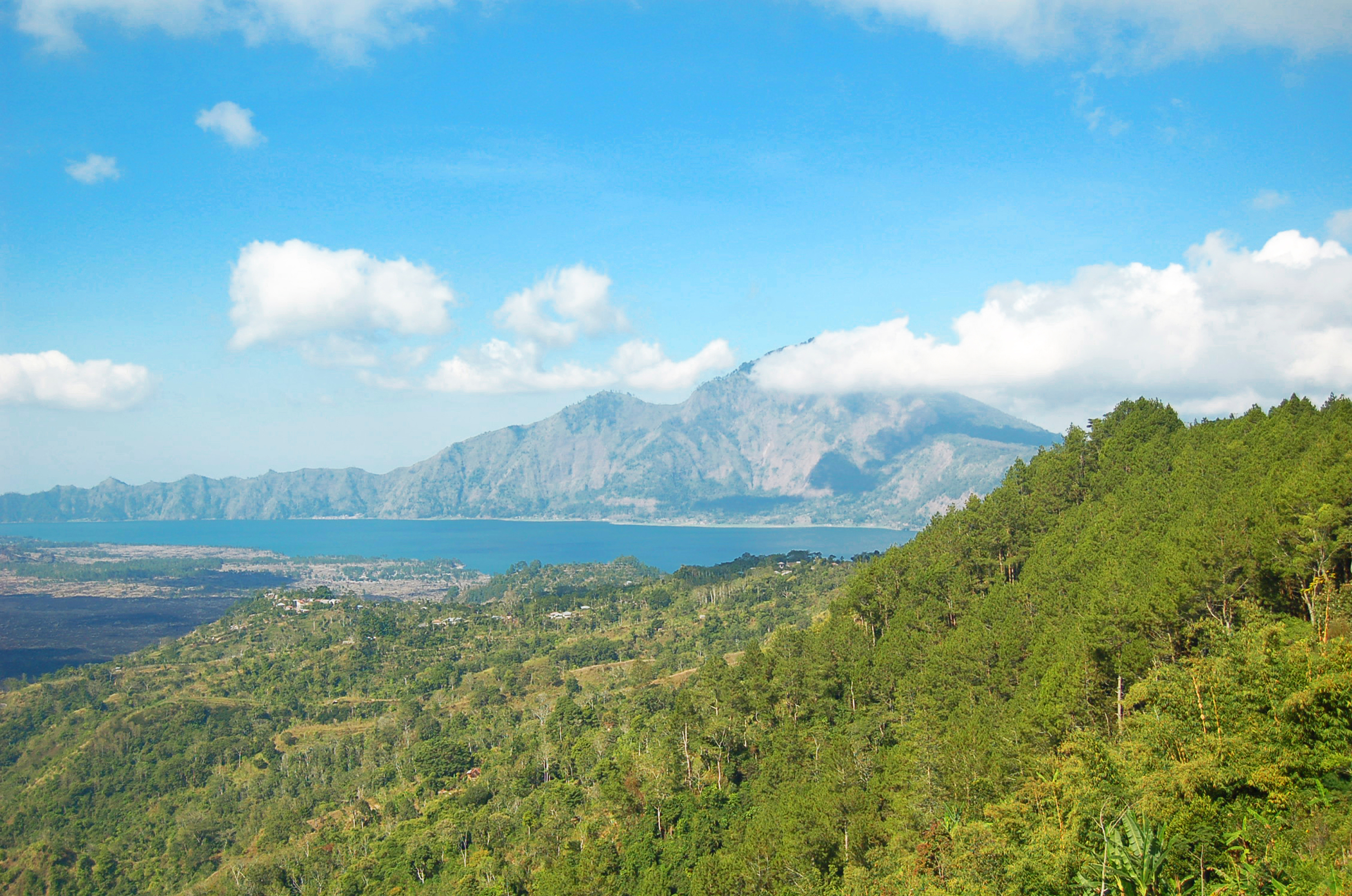 Betagende udsigt over Lake Buyan omgivet af frodige grønne bakker og bjerge på Bali i Indonesien under klar blå himmel