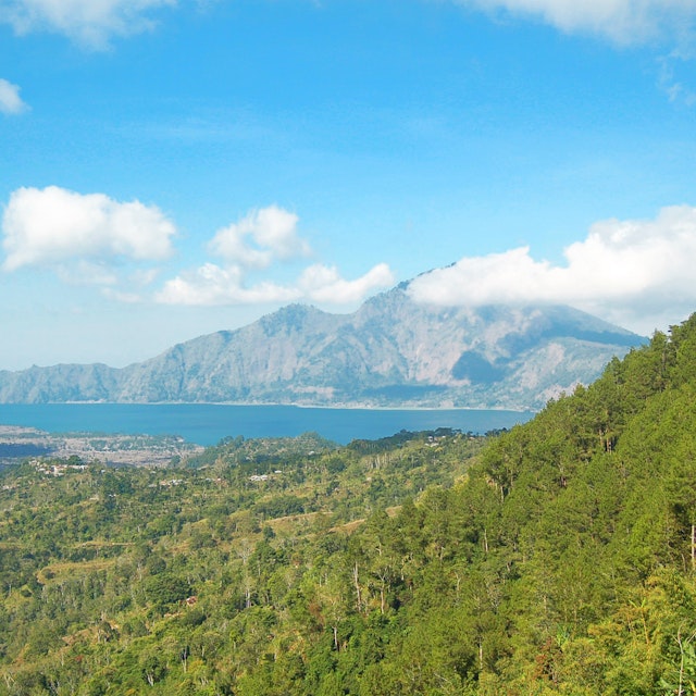 Betagende udsigt over Lake Buyan omgivet af frodige grønne bakker og bjerge på Bali i Indonesien under klar blå himmel