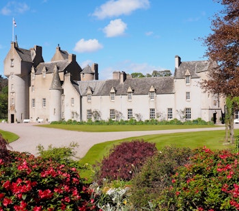 Ballindalloch Slot i de skotske højlande med smukke blomsterhaver og blå himmel