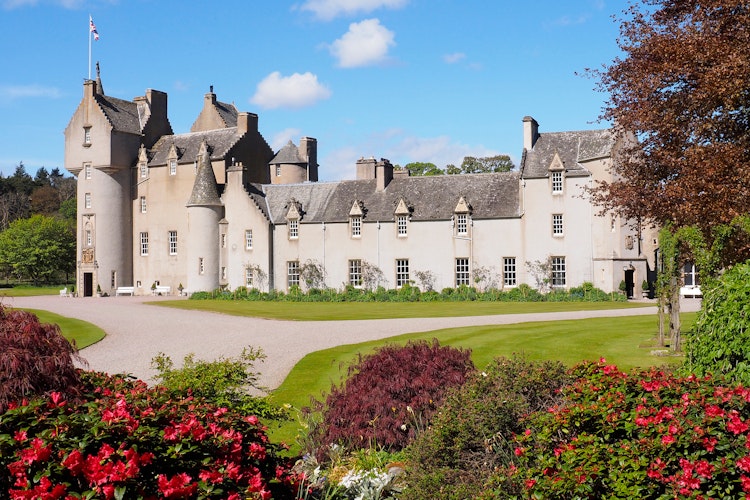 Ballindalloch Slot i de skotske højlande med smukke blomsterhaver og blå himmel