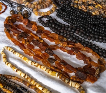 Farverige baltiske ravsmykker og perler på et traditionelt marked i Baltikum, viser polerede ravkæder i forskellige gyldne og mørke nuancer