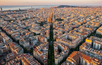 Betagende luftudsigt over Barcelonas Eixample-kvarter med den ikoniske Sagrada Familia basilika ved solopgang i Catalonien, Spanien