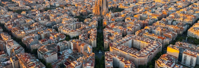 Betagende luftudsigt over Barcelonas Eixample-kvarter med den ikoniske Sagrada Familia basilika ved solopgang i Catalonien, Spanien