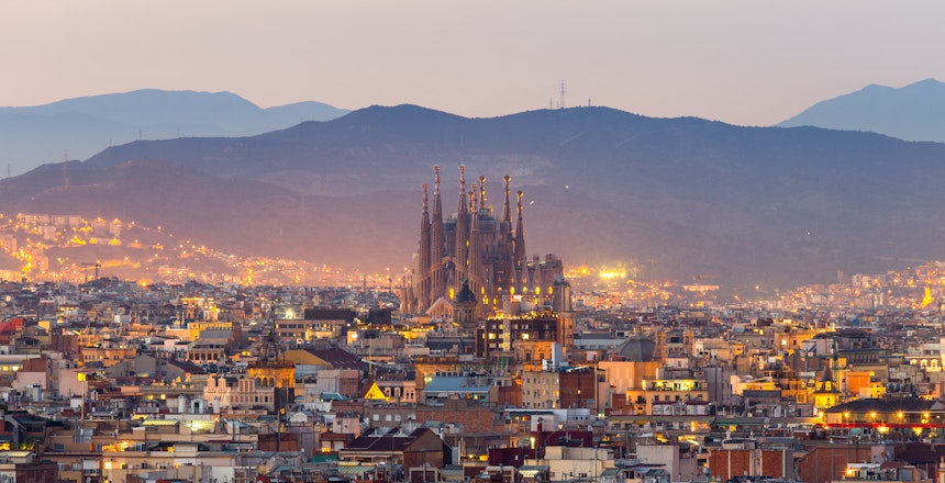 Betagende luftpanorama over Barcelona med Sagrada Familia katedral badet i skumringens gyldne lys og byens imponerende skyline