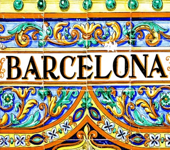 Dekorativt Barcelona-skilt på en farverig mosaikvæg, der viser byens karakteristiske modernistiske kunststil i Catalonien, Spanien