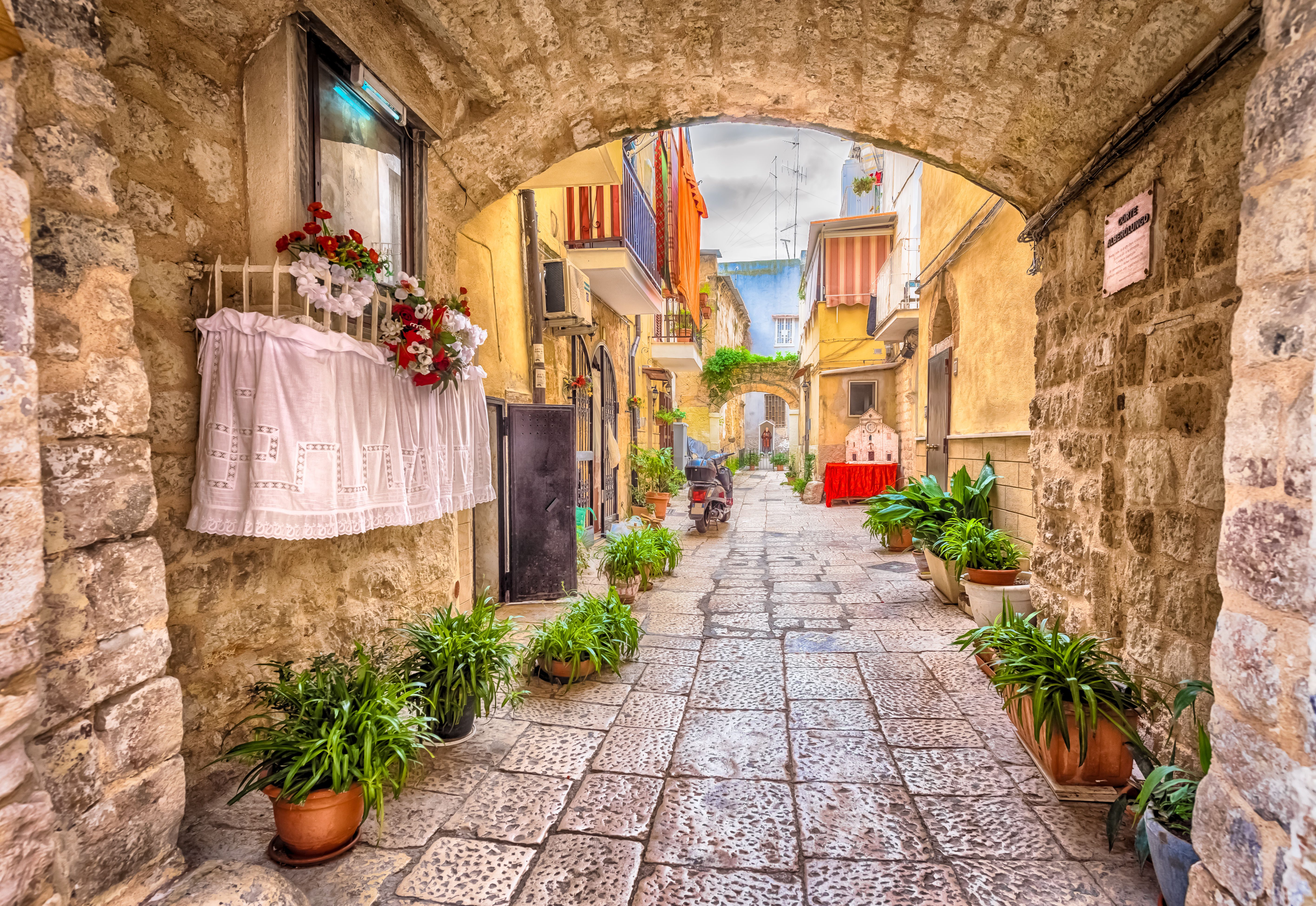 Charmerende smal gyde med hvide bygninger og stentrin i den historiske gamle bydel i Bari, Puglia, Syditalien