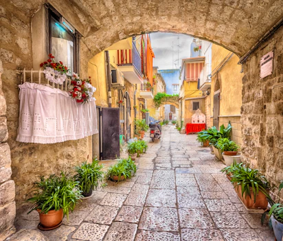 Charmerende smal gyde med hvide bygninger og stentrin i den historiske gamle bydel i Bari, Puglia, Syditalien