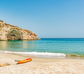 Idyllisk sandstrand ved Barr Al Jissah nær Muscat i Oman med krystalklart vand og majestætiske klipper langs den smukke kystlinje