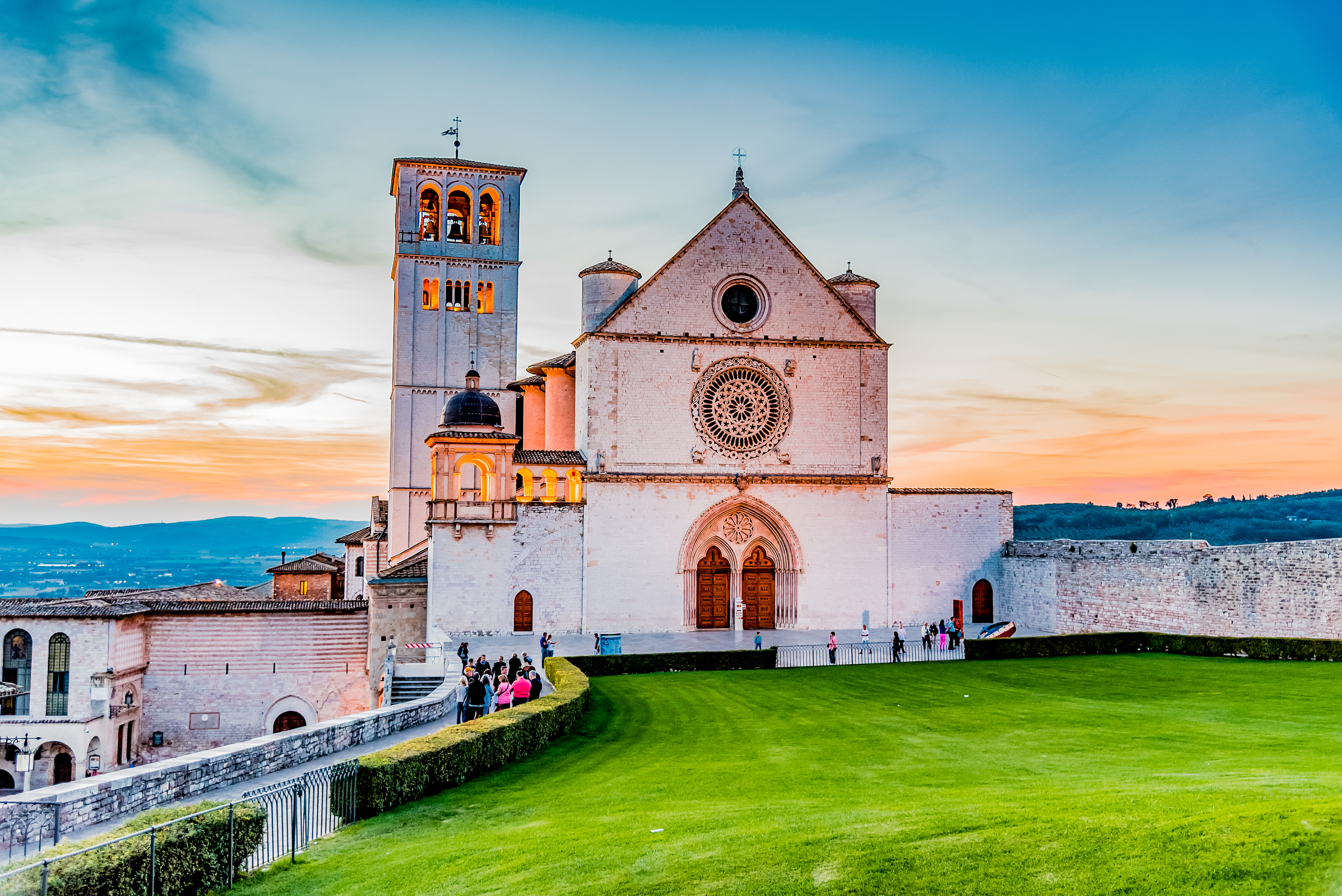 Den majestætiske San Francesco-basilika i Assisi badet i gyldent solnedgangslys - et UNESCO verdensarvssted med berømte fresker af Giotto og Cimabue, som vi besøger på vores sidste cykeldag