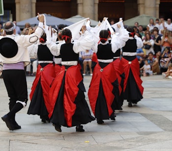 Traditionel baskisk folkedans med dansere i farverige røde og sorte dragter under en kulturfestival i Bilbao, Spanien