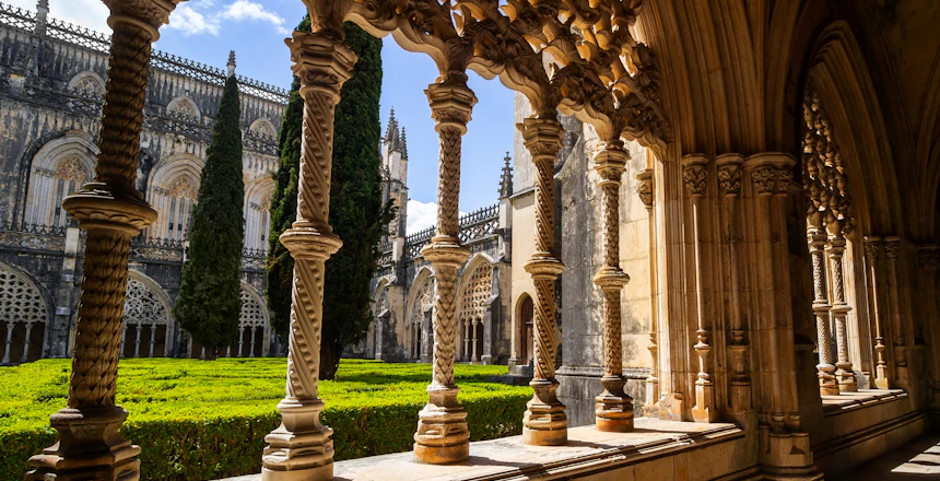 Smukke stensøjler og buer i klostergangen ved Batalha-klosteret i Portugal med karakteristisk sengotisk og Manueline arkitektur