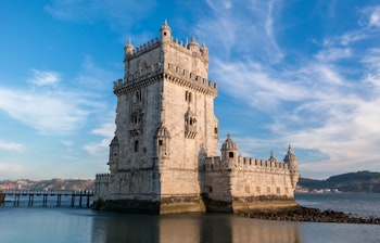 Det historiske Belem Tårn ved solnedgang med smuk refleksion i vandet - et ikonisk vartegn i Lissabon, Portugal