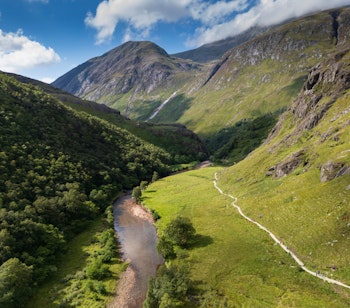Luftfoto af den snoede Water of Nevis-flod gennem grønne dale ved Ben Nevis-bjerget i det skotske højland på vores rundrejse til Sagnomspundne Skotland