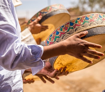Traditionel berberisk bryllupsceremoni med kvinder i farverige dragter der danser til autentisk musik i Merzouga, Marokko