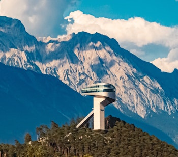 Sommerudsigt over den berømte Berg Isel skihopstårn med de majestætiske Nordkette bjerge i baggrunden under blå himmel nær Innsbruck i Østrig