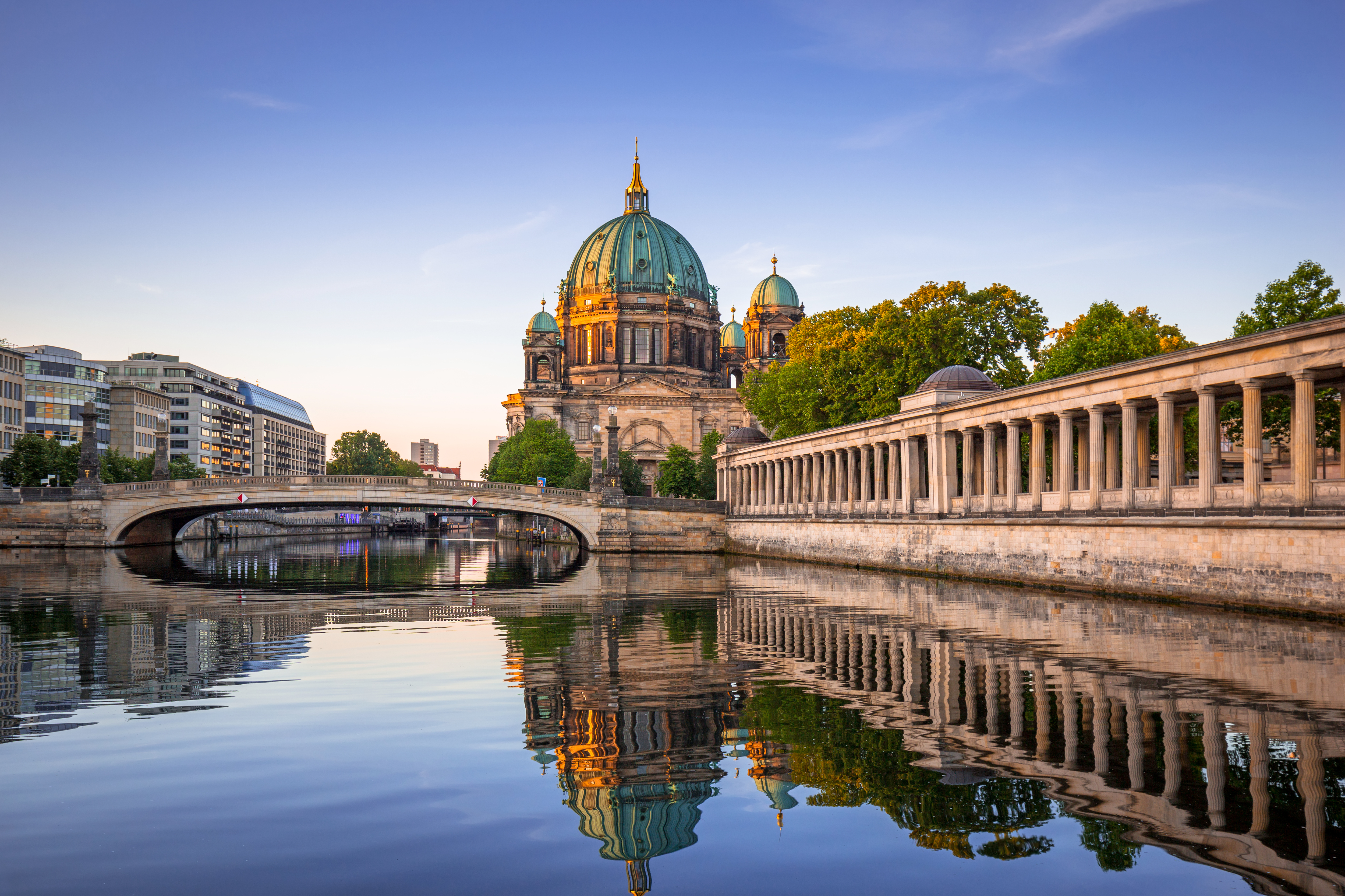 Berlins smukke domkirke spejler sig i Spree-floden ved solnedgang med historisk søjlegang