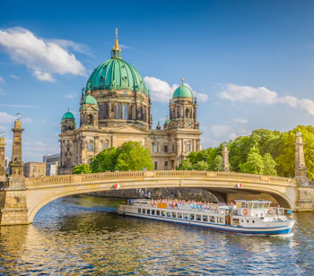 Berlin Domkirke ved Spree floden med turistbåd og historisk bro