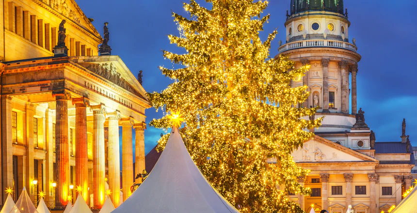 Berlin julemarked på Gendarmenmarkt med oplyst katedral og juletræ om aftenen