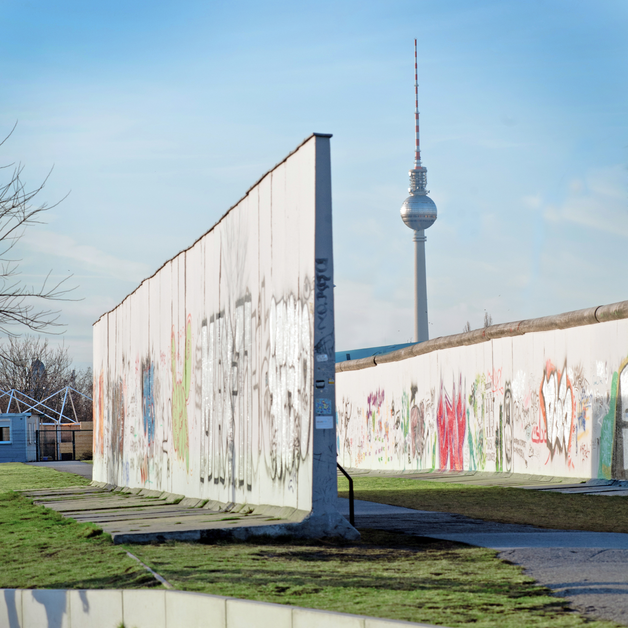 Berlins historiske mur med farverig graffiti og TV-tårnet i baggrunden