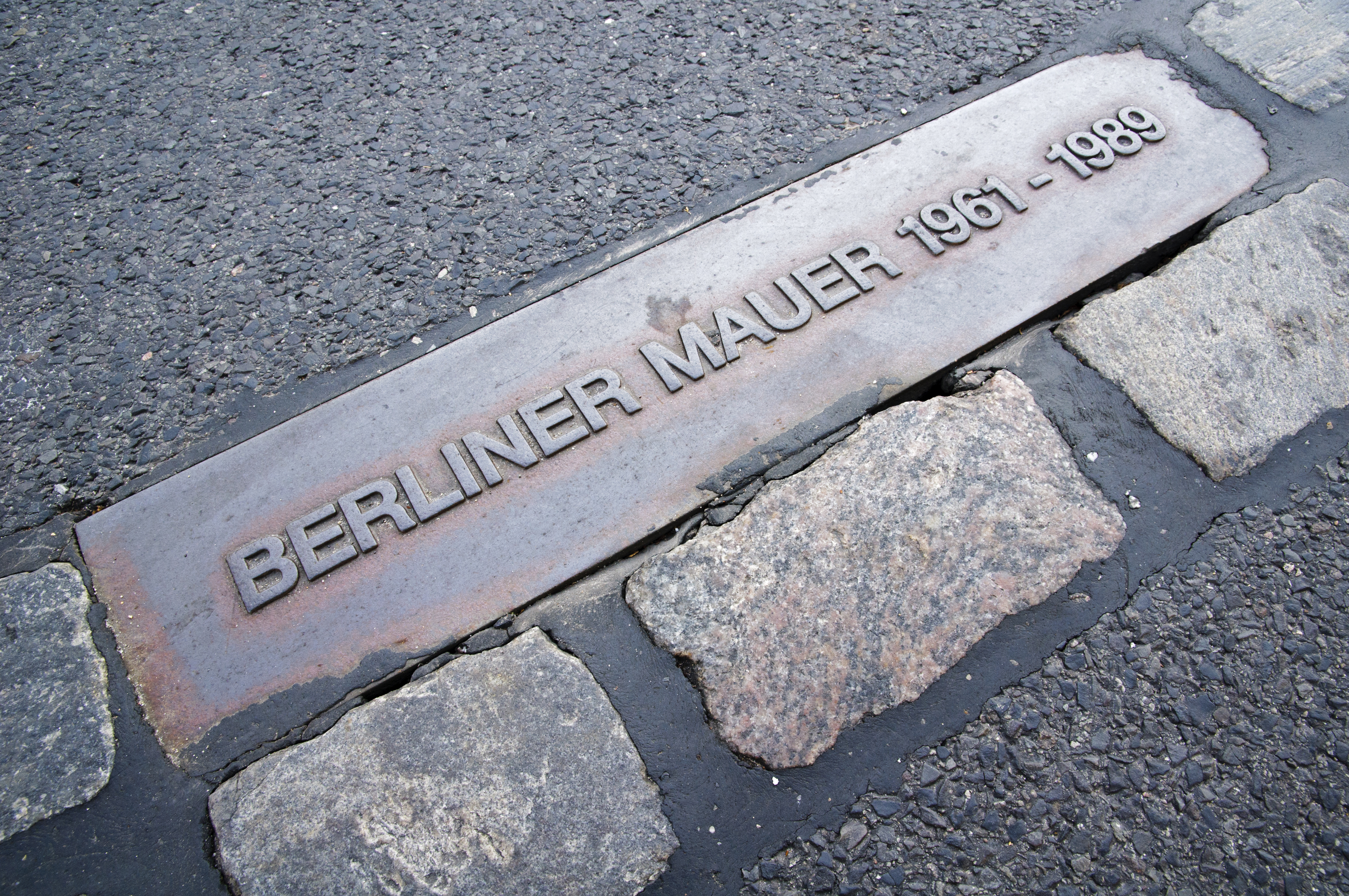 Berliner Mur mindesten i brolægget viser historiske datoer 1961-1989 i Berlin