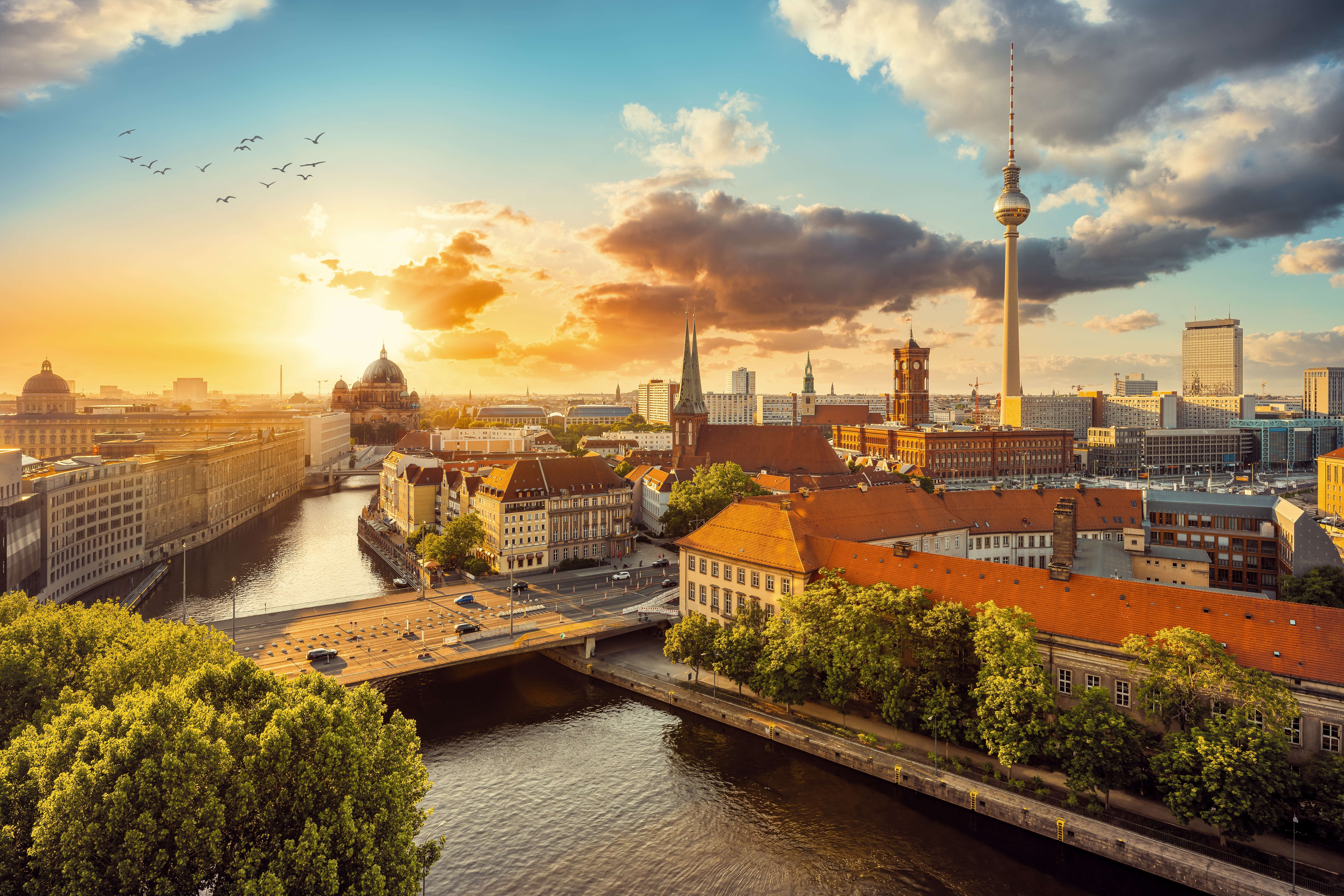 Luftfoto af Berlins skyline ved solnedgang med TV-tårnet, Berlin Domkirke og floden Spree badet i gyldent aftenlys