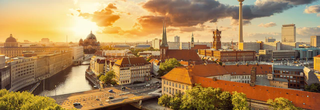 Luftfoto af Berlins skyline ved solnedgang med TV-tårnet, Berlin Domkirke og floden Spree badet i gyldent aftenlys