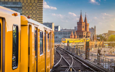Gult U-Bahn tog ved Oberbaum Broen i Berlin under solnedgang