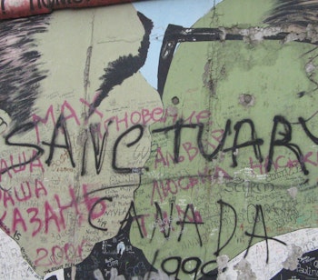 Historisk fragment af Berlinmuren med "Sanctuary" graffiti, der symboliserer frihed og genforening efter Tysklands deling