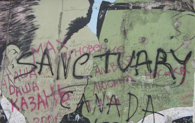 Historisk fragment af Berlinmuren med "Sanctuary" graffiti, der symboliserer frihed og genforening efter Tysklands deling