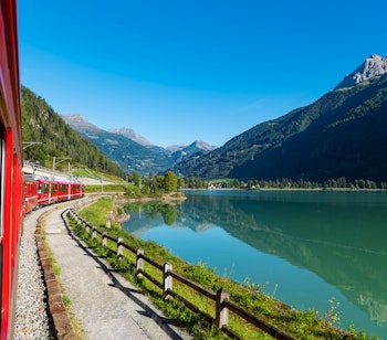 Det røde Bernina Express tog kører gennem det betagende landskab i de schweiziske alper, en UNESCO verdensarvsrute mellem Sankt Moritz og Tirano