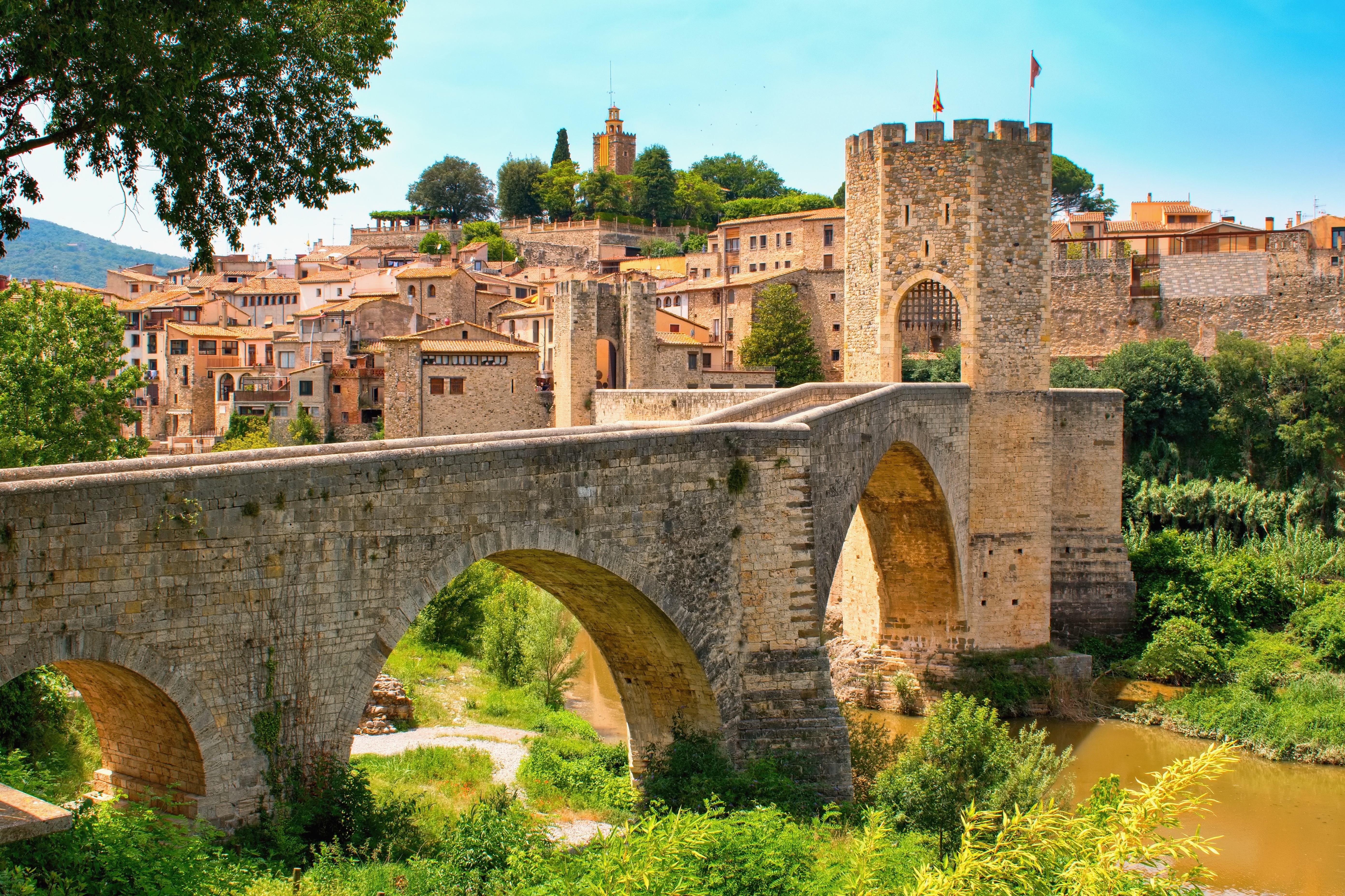 Smuk middelalderlig stenbro med buer over floden Fluvia i den historiske landsby Besalú i Catalonien, Spanien