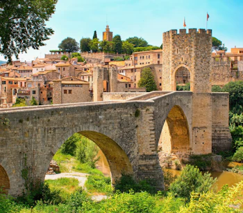 Smuk middelalderlig stenbro med buer over floden Fluvia i den historiske landsby Besalú i Catalonien, Spanien