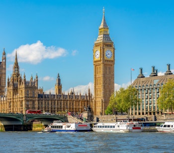 Det berømte Big Ben-ur og parlamentsbygningen ved Themsen med turistbåde i solskin, London