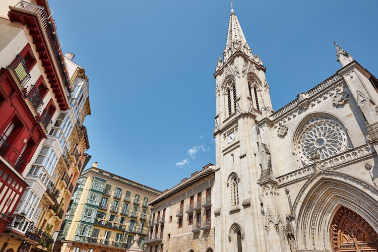 Gotisk katedral med høj spir og rosetvindue i Bilbaos gamle bydel omgivet af farverige traditionelle bygninger i Baskerlandet, Spanien