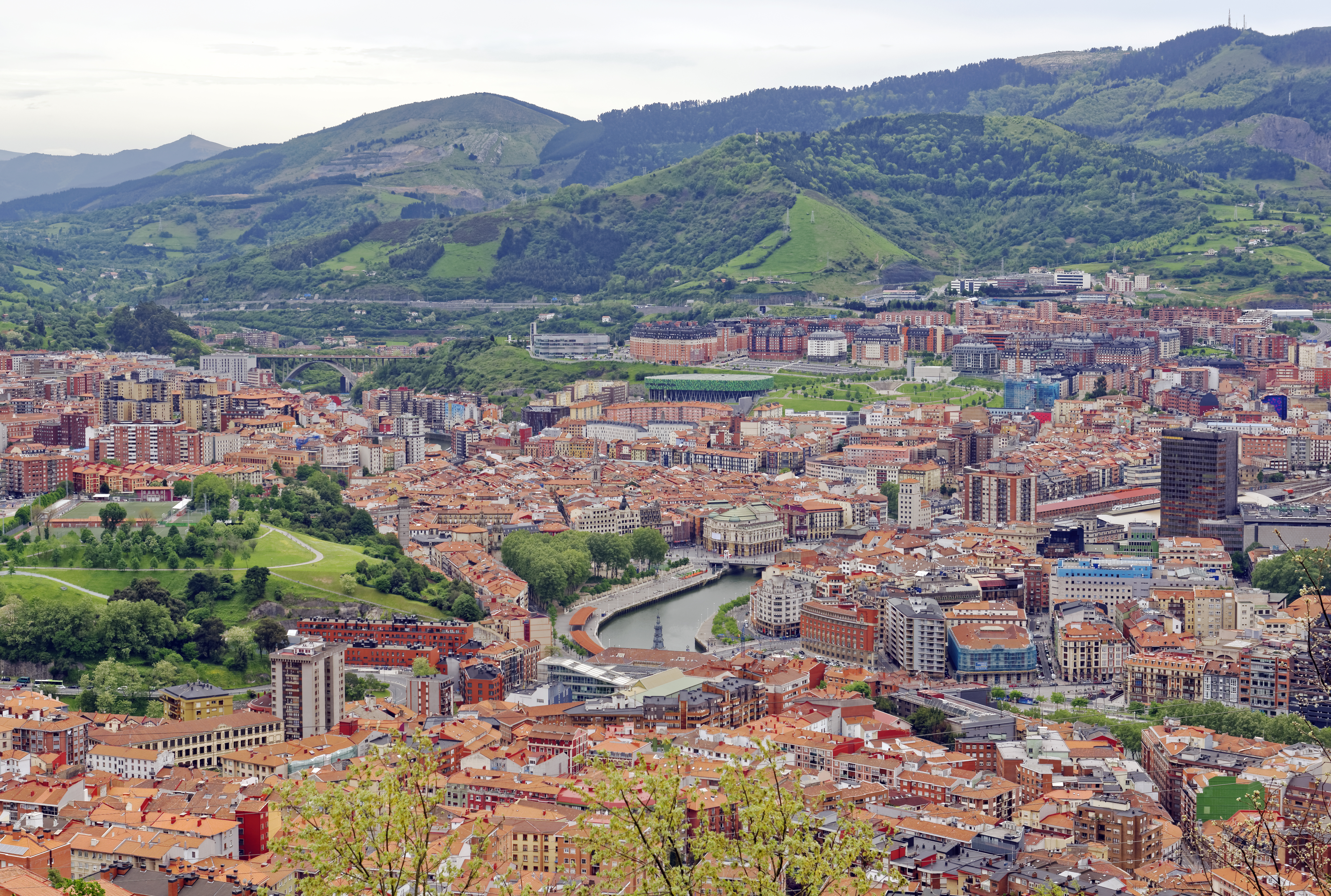 Panoramaudsigt over Bilbaos bycentrum fra Artxanda-bjerget med arkitektur, Nervion-floden og skyline under skyet himmel i Nordspanien