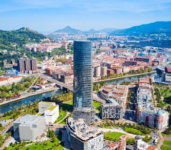 Panoramisk luftfoto af Bilbao med Iberdrola tårnet, floden og bjergene i Baskerlandet, Nordspanien