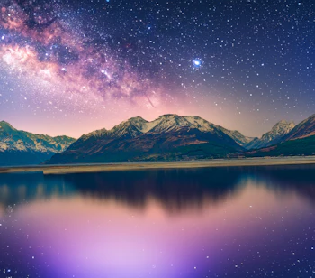 Spektakulært bjerglandskab med Mælkevejen og stjernehimmel reflekteret i bjærgsø om natten
