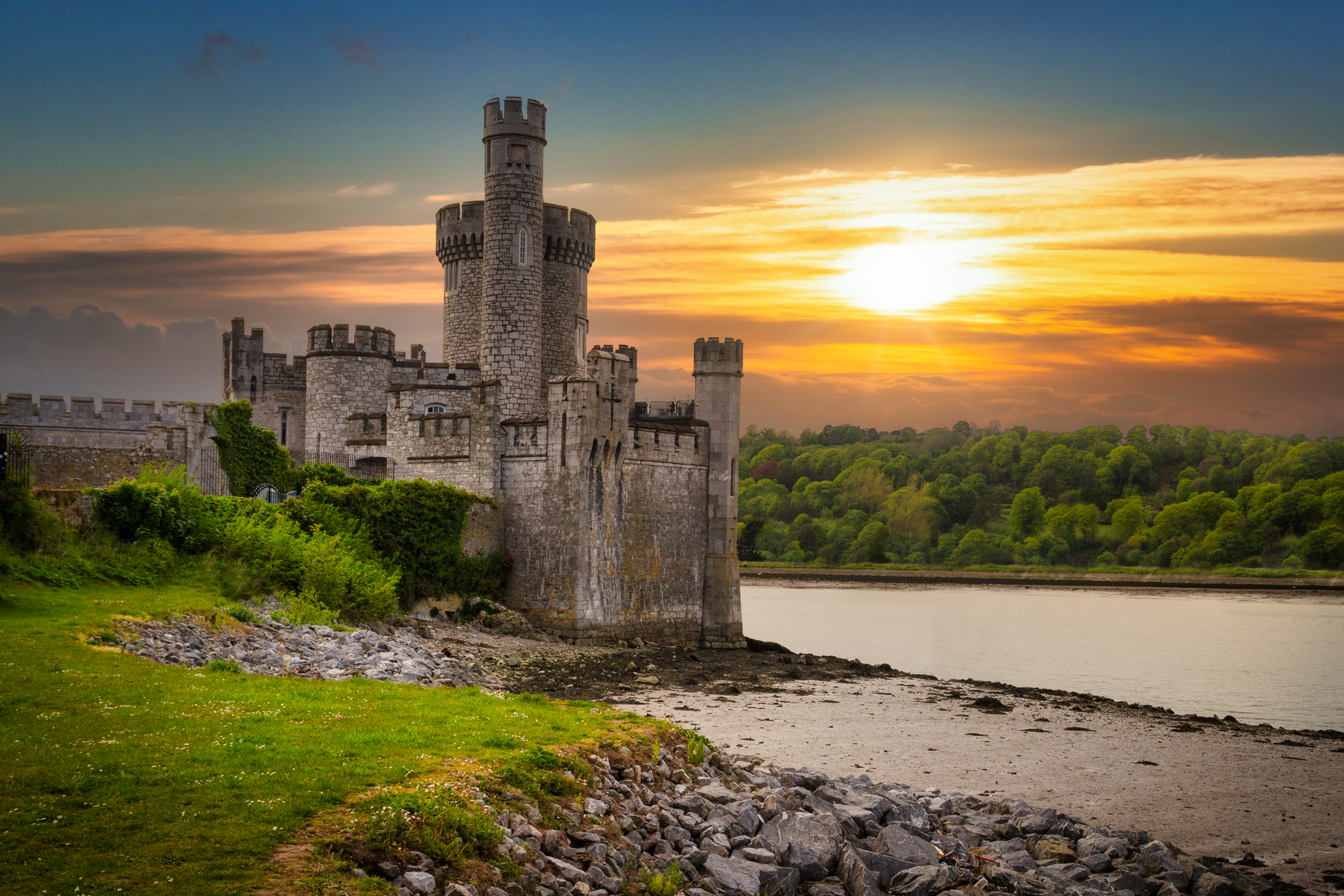 Det historiske Blackrock Castle og observatorium badet i gyldent solnedgangslys ved kysten af Cork i Irland, hvor middelalderarkitektur møder moderne videnskab