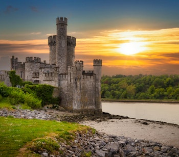 Det historiske Blackrock Castle og observatorium badet i gyldent solnedgangslys ved kysten af Cork i Irland, hvor middelalderarkitektur møder moderne videnskab