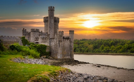 Det historiske Blackrock Castle og observatorium badet i gyldent solnedgangslys ved kysten af Cork i Irland, hvor middelalderarkitektur møder moderne videnskab