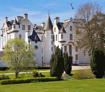 Den imponerende hvide facade af Blair Atholl Slot med velholdte haver i det skotske højland