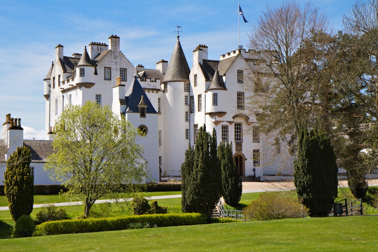 Den imponerende hvide facade af Blair Atholl Slot med velholdte haver i det skotske højland