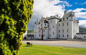 Sommerbillede af det historiske Blair Atholl slot omgivet af frodige træer i Skotland.