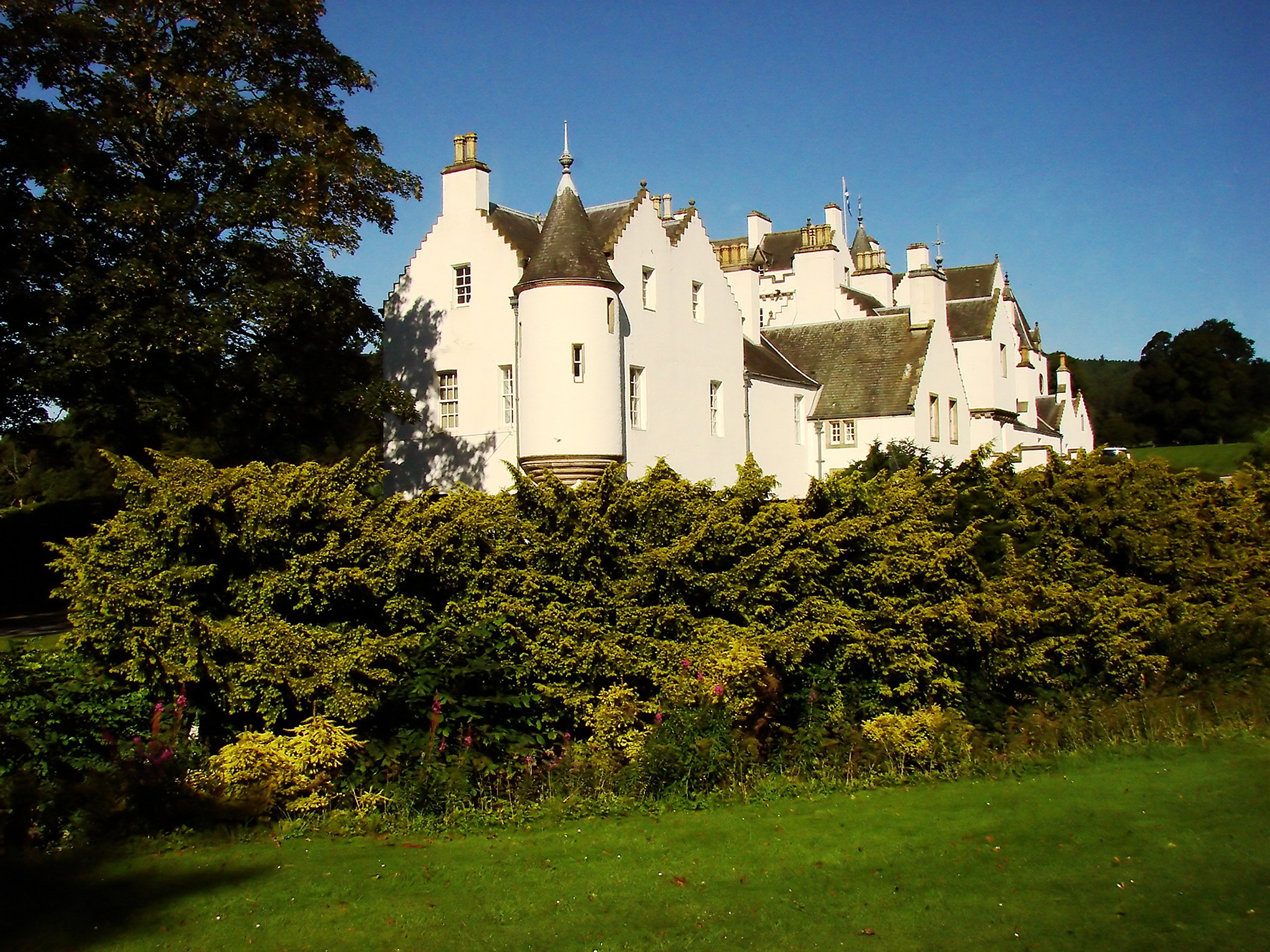Historisk Blair Castle med hvide mure og karakteristiske tårne omgivet af grønne haver i Skotland