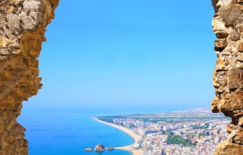 Betagende udsigt over Blanes strand og Middelhavskyst gennem stenport i St. John slottet, Costa Brava, Spanien