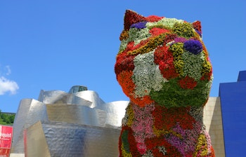 Farverig blomsterhund-skulptur ved Guggenheim-museet i Bilbao, en ikonisk turistattraktion i Spanien