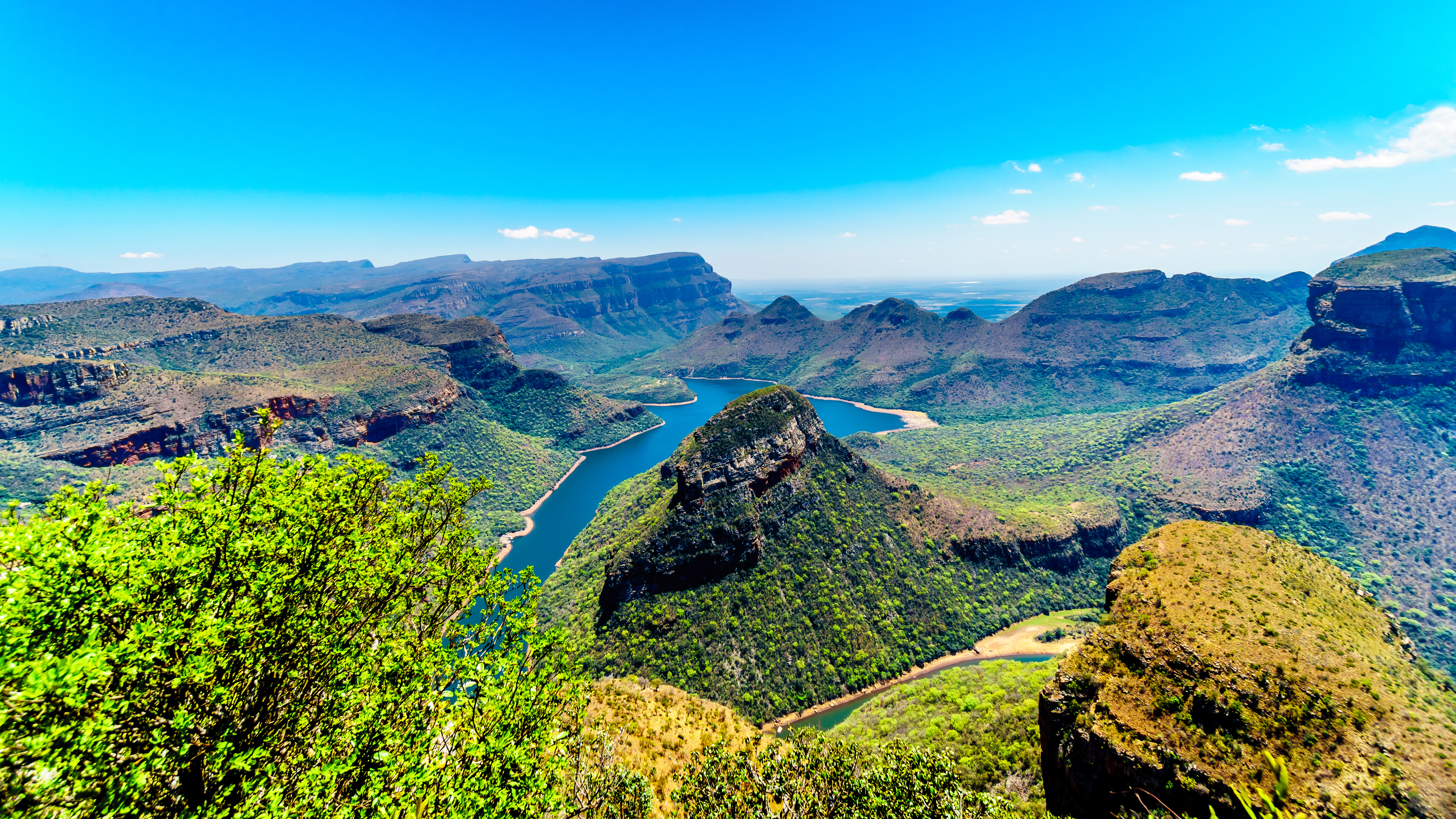 Panoramaudsigt over Blyde River Canyon i Mpumalanga, Sydafrika, med den snoende flod omgivet af frodige grønne bjerge og dramatiske klippeformationer